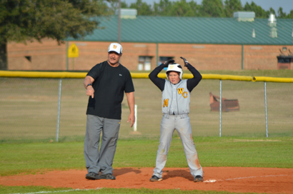 Tyler Goodwin receives instruction from Coach Jimmy Hughes after reaching third base.